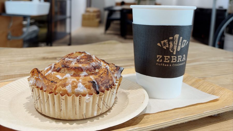 ZEBRA Coffee & Croissant のトレー。アイシングのかかったシナモンロールとコーヒー