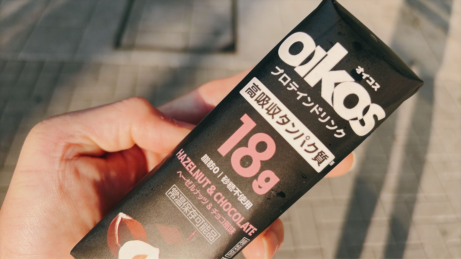 手に持ったオイコスのプロテインドリンク ヘーゼルナッツ&チョコ