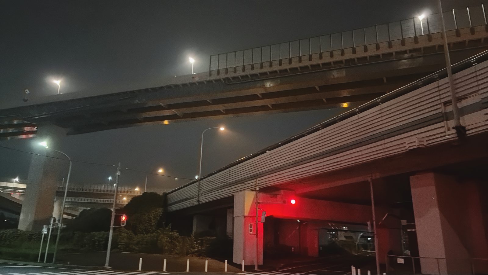 夜明け前、高速の高架が交差するジャンクションの下。信号が赤く光っている