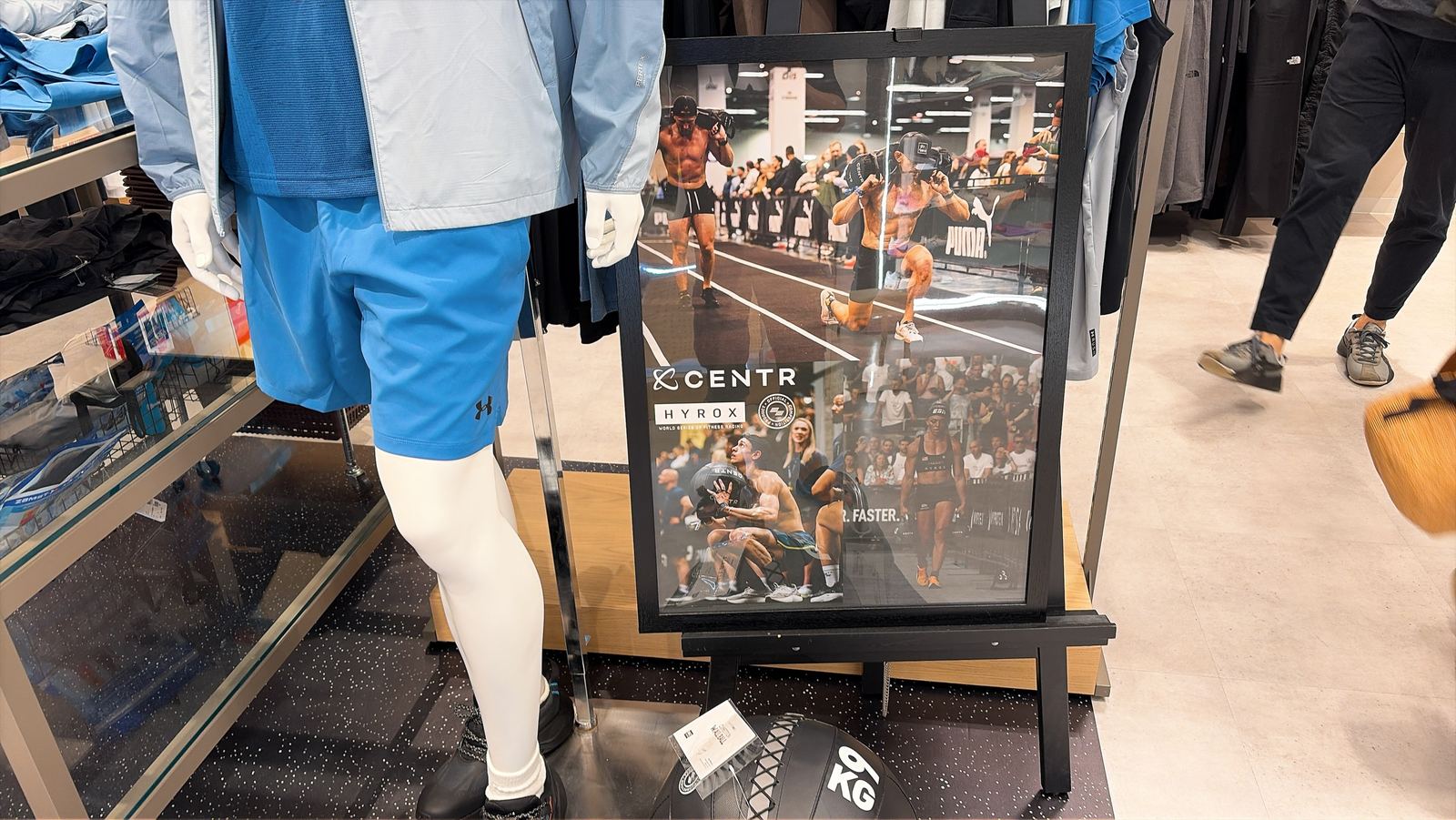 スポーツショップの売り場。CENTRとHYROXのポスターの下に、9kgのウォールボールが置いてある