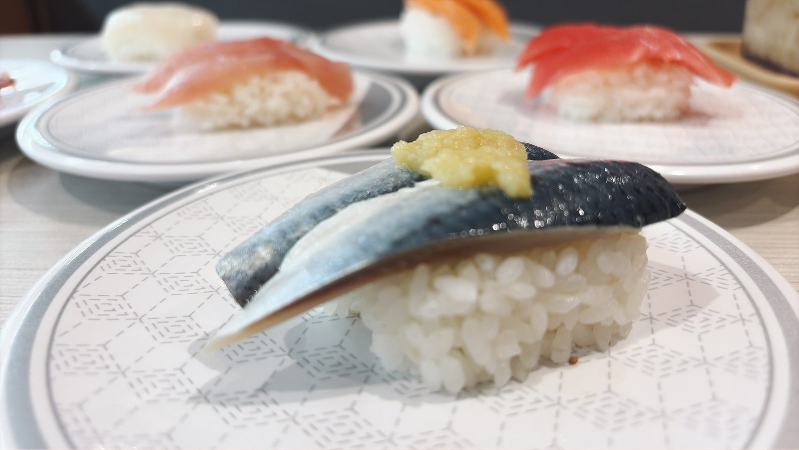 はま寿司のしめ鯖の握り。上にすりおろした生姜がのっている。奥にまぐろとサーモンの皿