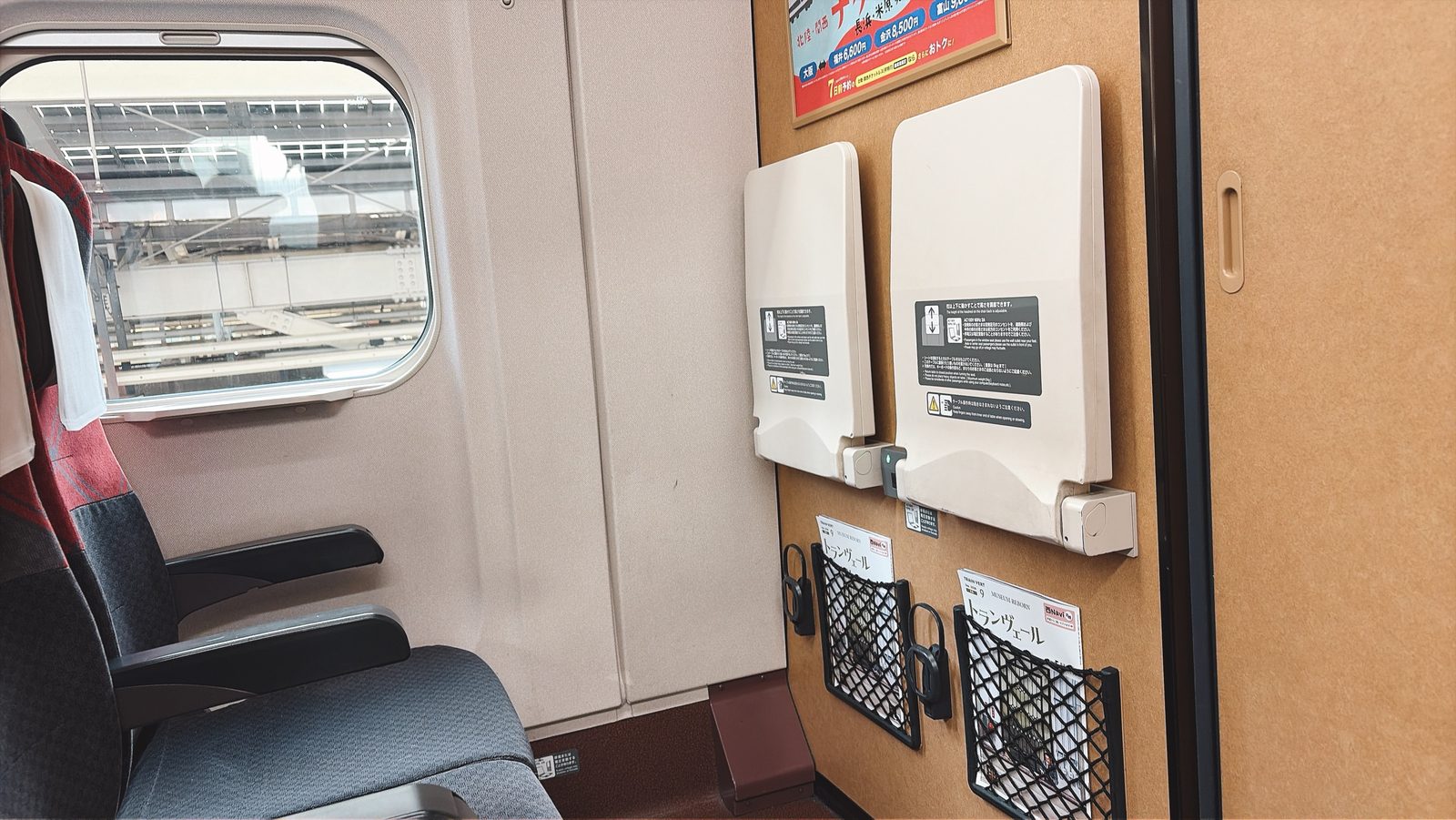 新幹線の座席と窓。前の壁にテーブルと網のポケット