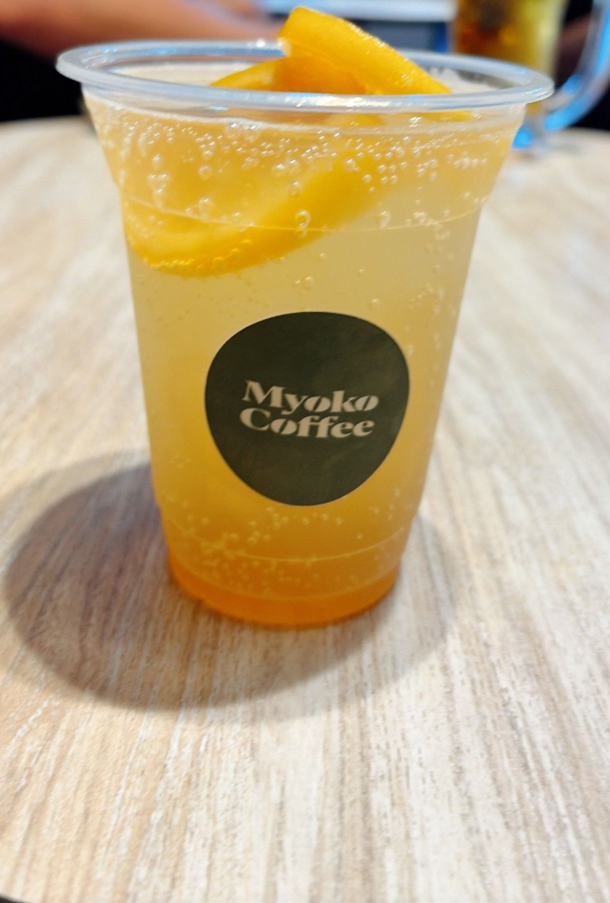 Myoko Coffee のカップに入った、オレンジの輪切り入りの炭酸ドリンク